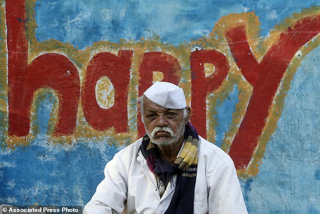 A farmer sits next to a graffiti at the end of their six day long march on foot, in Mumbai, India, Monday, March 12, 2018. Tens of thousands of farmers from across western India have arrived in Mumbai demanding, among other things, a waiver of farm loans and fair prices for their produce as India's agriculture sector struggles amid years of declining earnings. The farmers reached India's business capital Monday after marching on foot for up to six days and plan to surround the state legislature of the western state of Maharashtra in Mumbai. (AP Photo/Rajanish Kakade)